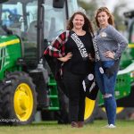 Melody Riedl and Emma Wheeler standing in front of a John Deere tractor