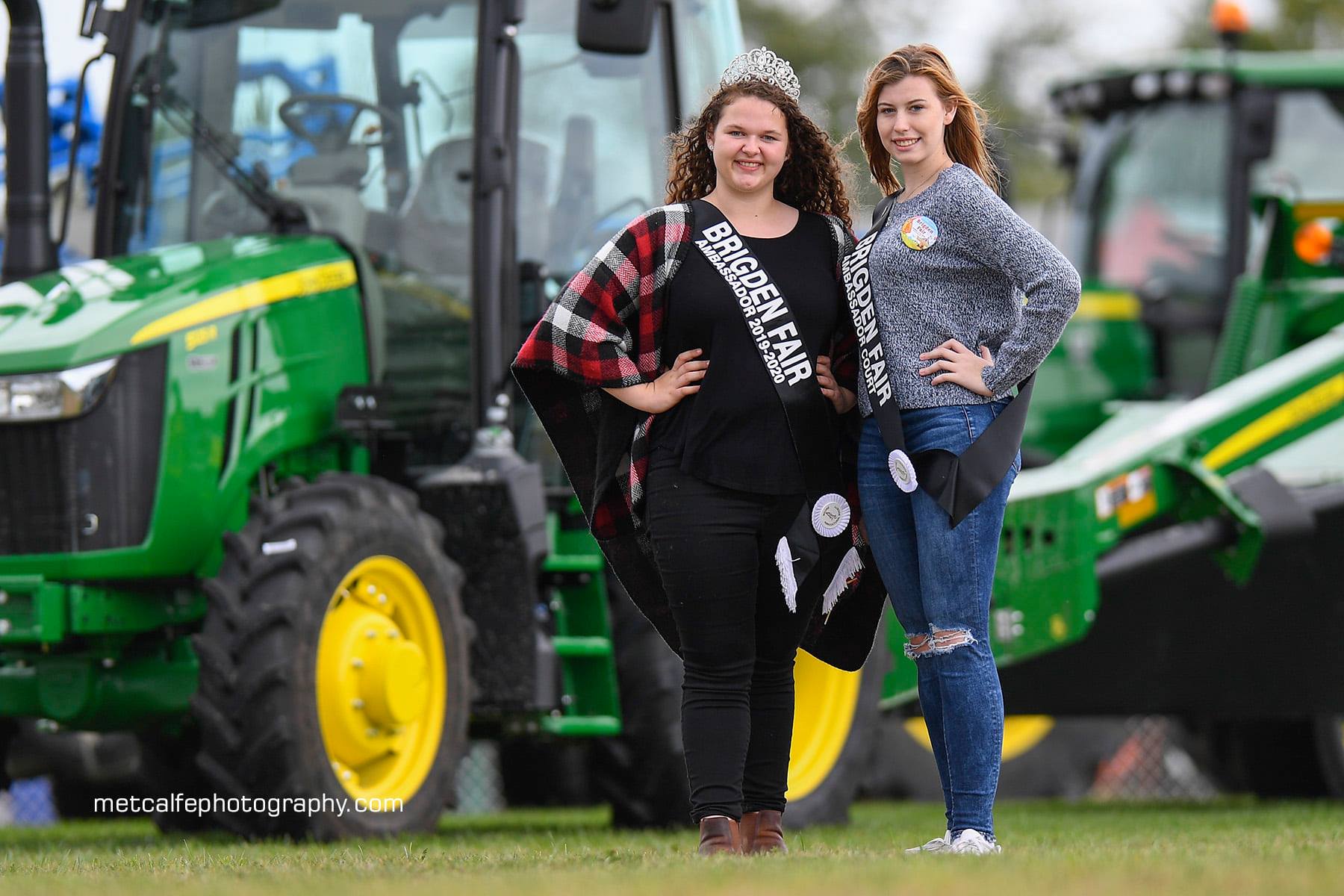 Melody Riedl and Emma Wheeler standing in front of a John Deere tractor